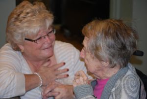 A long-term care resident holding hands and talking with a loved one