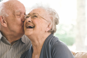 A senior man giving a senior woman a kiss on the cheek