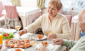 A senior couple enjoying pizza and wine together in a restaurant
