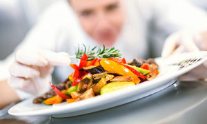 A chef putting the finishing touches on a plate of stir fry