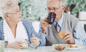 A senior couple enjoying coffee and cookies together