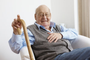 A senior man sitting in a chair with a cane