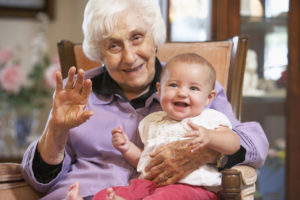 A senior woman holding a young baby