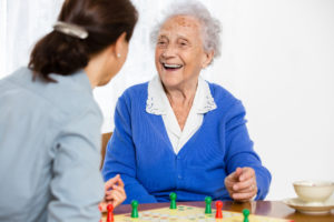 A senior woman playing a board game with a younger woman