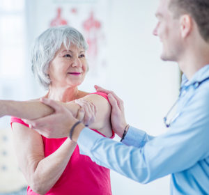 A healthcare worker helping a senior woman to stretch out her arm