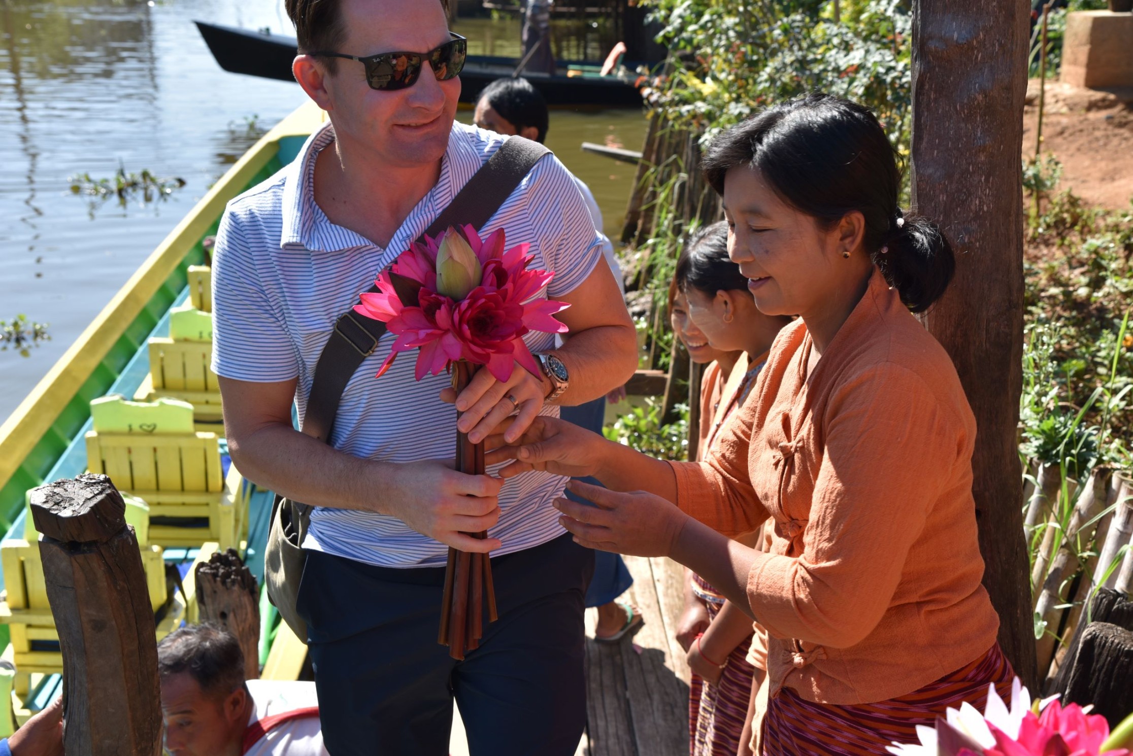 peopleCare CEO Brent Gingerich holding a flower next to a Myanmar resident