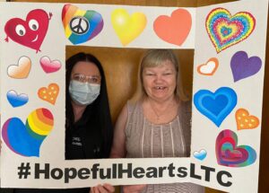 Long-term care home staff and resident in a fun photo frame