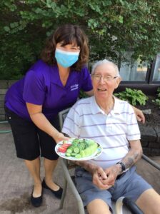 Staff member and resident of long-term care home with vegetables from the garden