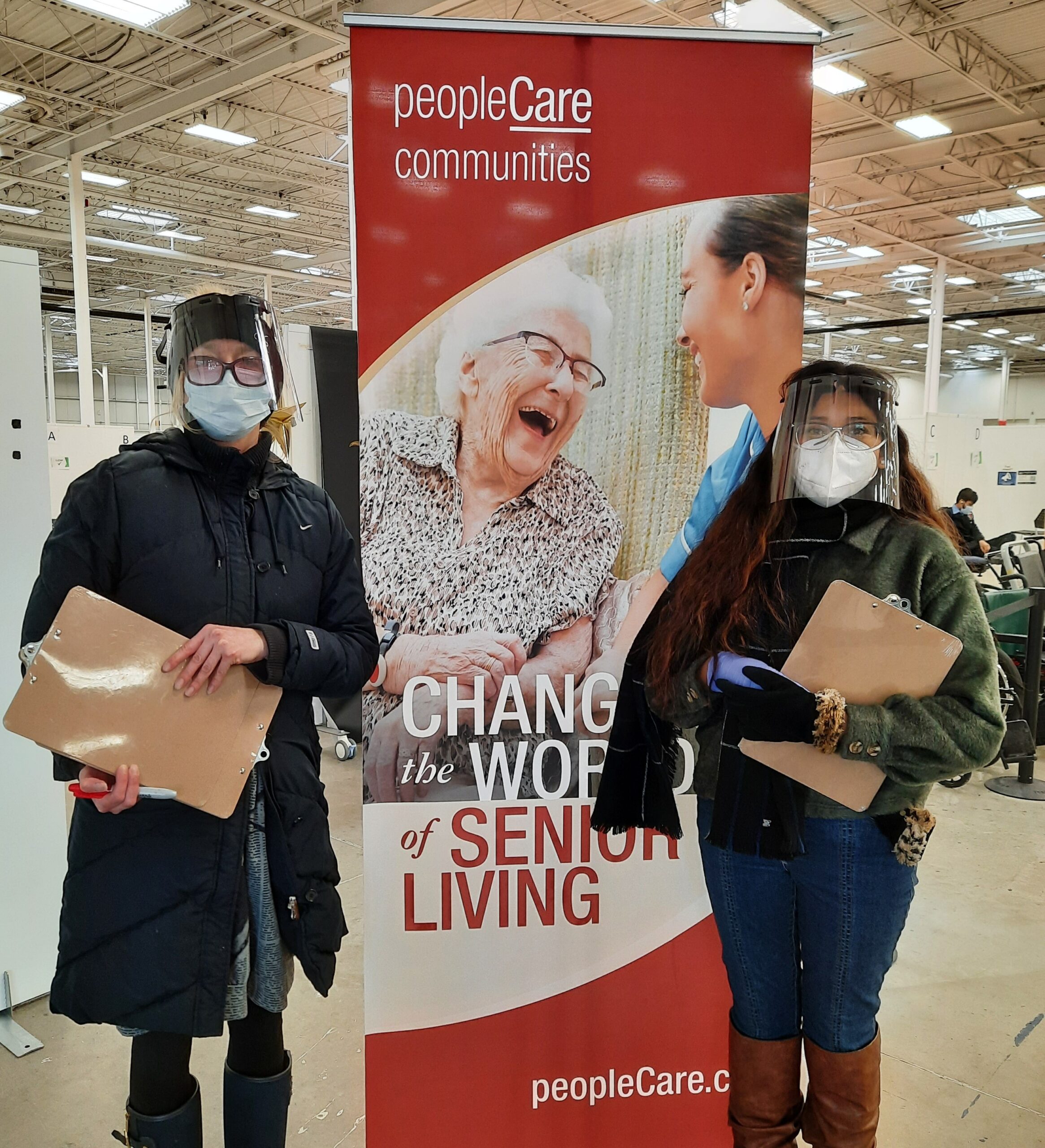 Screeners at the Cambridge Pinebush vaccination clinic standing next to a peopleCare banner