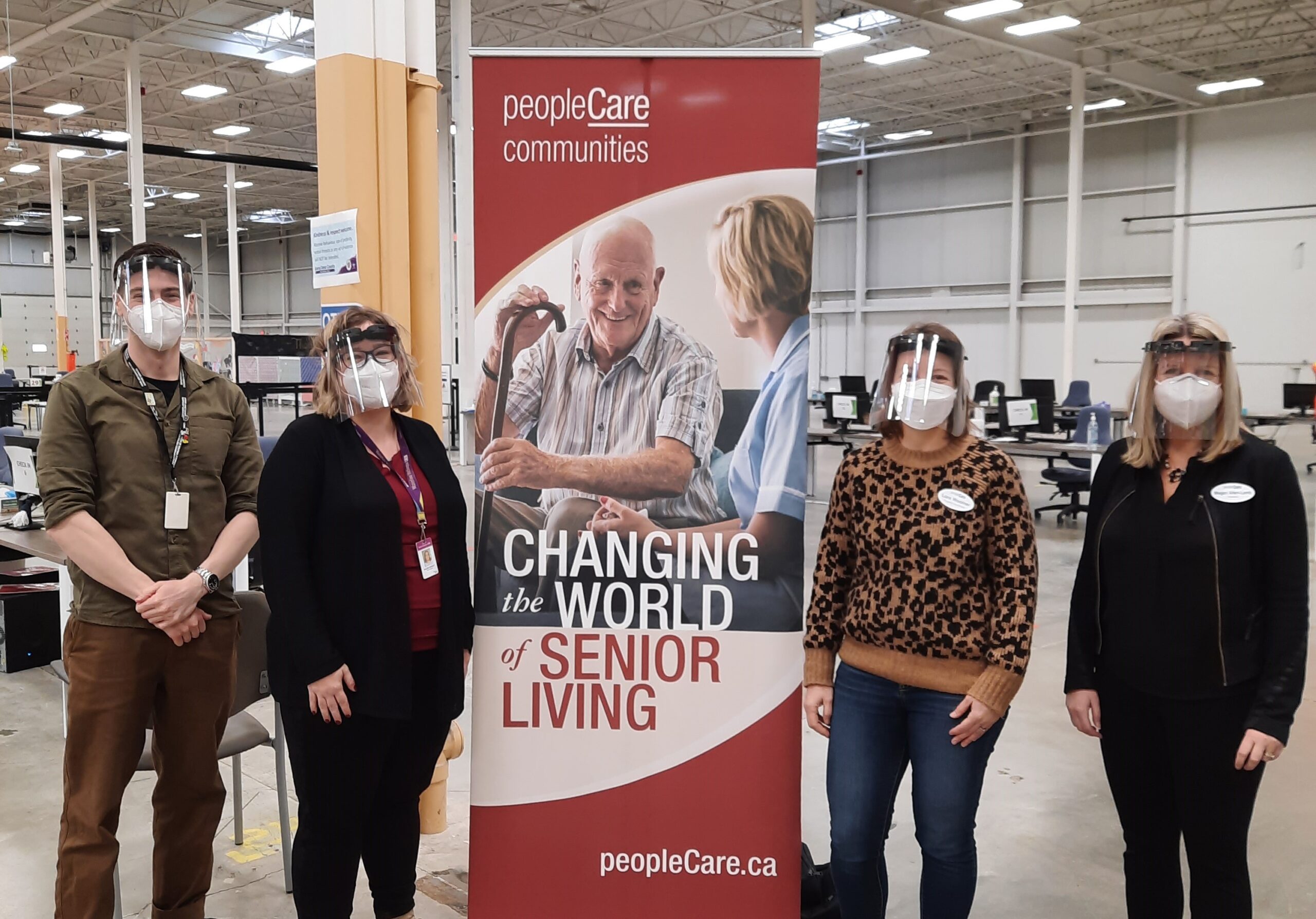 peopleCare team members and team members from the LHIN standing next to a peopleCare banner at the vaccine clinic