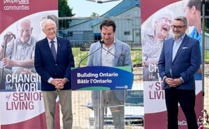 On the left is Oxford MPP Ernie Hardeman, , Brent Gingerich, CEO of peopleCare is in the middle, and and on the right is Paul Calandra, Minister of Municipal Affairs and Housing. Brent is speaking at the podium
