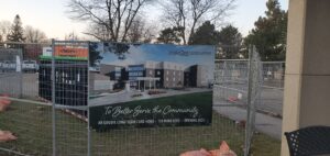 A sign with the text: "to better serve the community. AR Goudie Long-term care home. 128 more beds. OPENING 2025